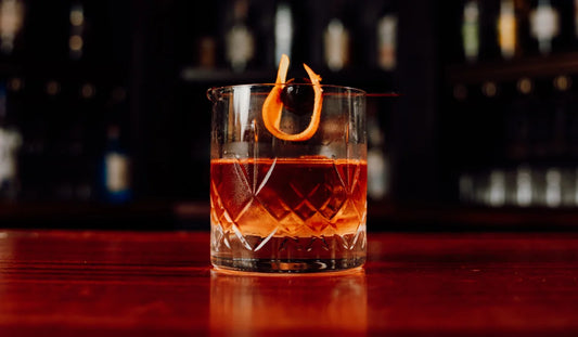 Old Fashioned in a glass with an orange twist and cherry garnish